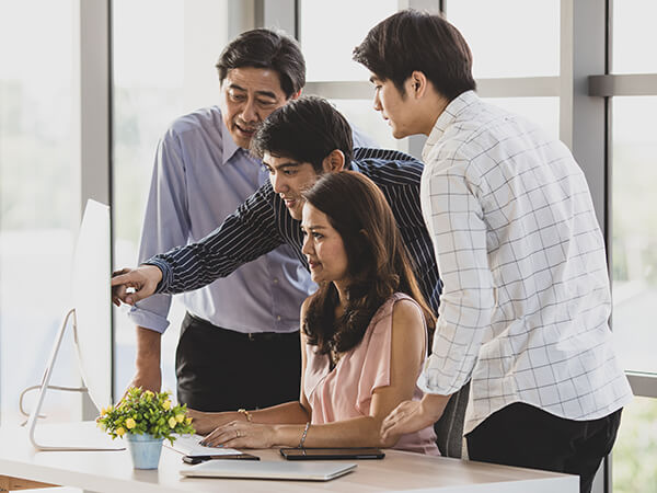 大人4人がパソコンの前で話し合っている